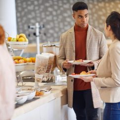 Young colleagues talking while picking a food in a pleasant atmosphere at company canteen. People, job, company, business concept.